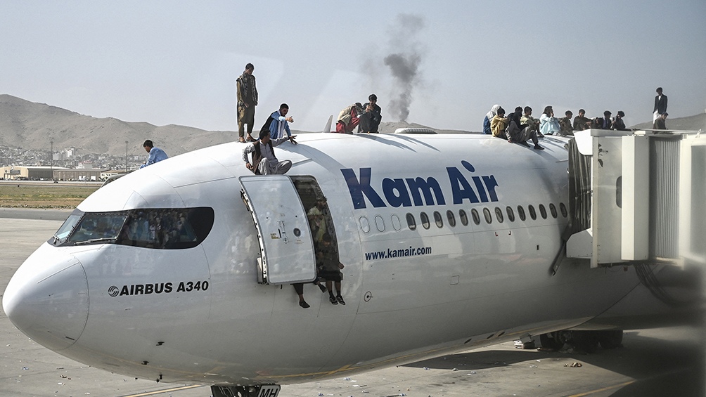 Videos colgados en las redes mostraban a grupos de jóvenes que se agarraban de las escaleras, intentando subir a un avión. Foto: AFP.