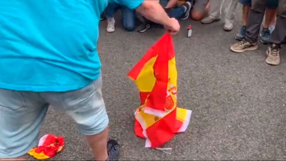 En las imágenes difundidas en las redes se puede ver a un grupo de manifestantes y fotógrafos alrededor de un hombre que prende fuego las banderas del Estado Español.