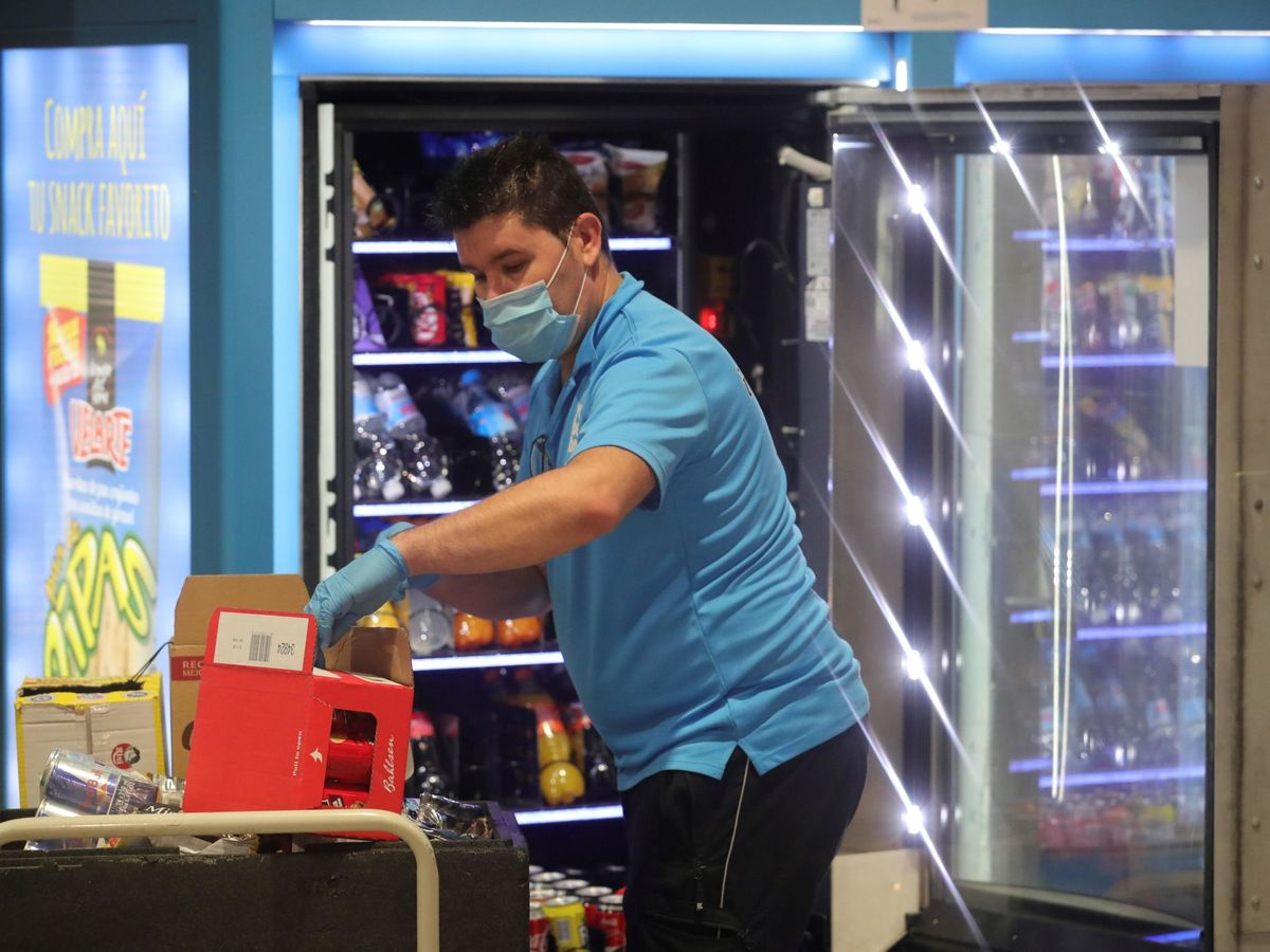 Foto: Un trabajador repone una máquina expendedora. (EFE/Juanjo Martín)