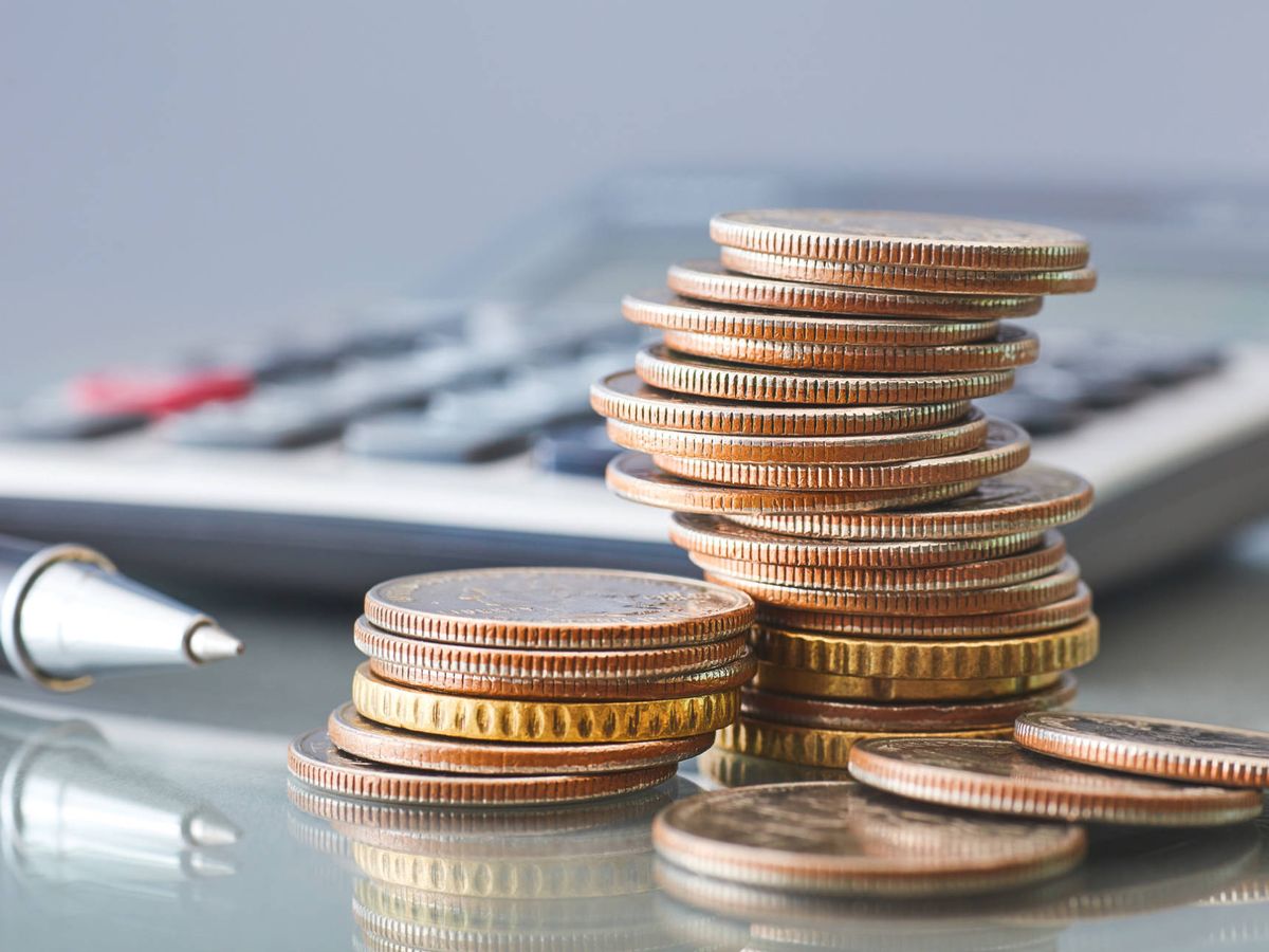 Foto: Montones de monedas junto a una calculadora. (iStock)