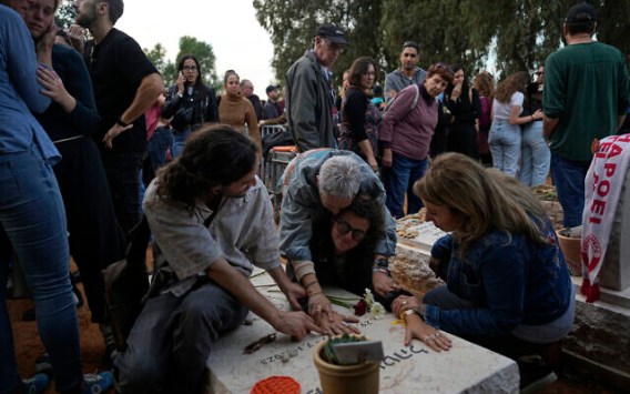 Amigos que asisten al funeral de Alon Shamriz, de 26 años, lloran ante la tumba de una víctima del ataque del 7 de octubre enterrada en el mismo cementerio en el Kibbutz Shefayim