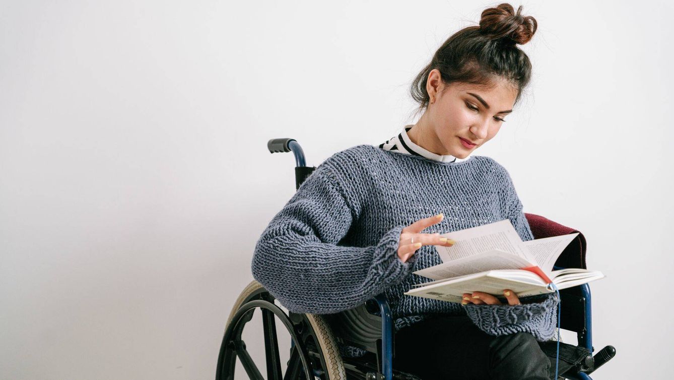 Mujer lee un libro en silla de ruedas (Ivan Samkov/Pexels)